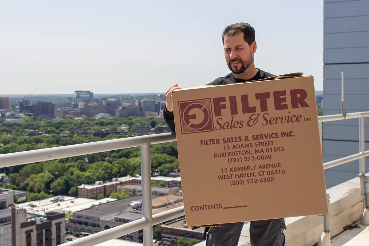 air filtration service tech with box on rooftop